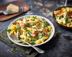 a plate of pasta with asparagus, tomatoes and other toppings on it