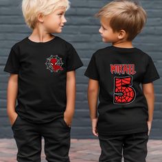 two young boys standing next to each other wearing matching black t - shirts with spiderman on them