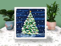 a card with a christmas tree on it next to potted plants and a planter