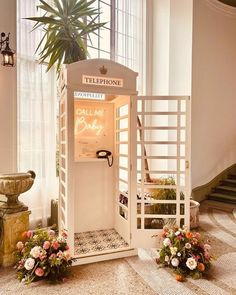 an old fashioned phone booth with flowers on the floor