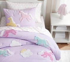 a bed with pink and purple comforters on top of it