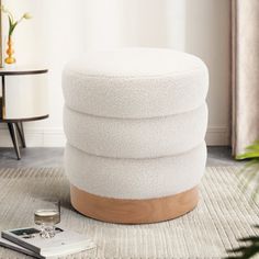 a white round ottoman sitting on top of a rug next to a table and chair