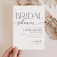 a person holding up a white card with the words bridal shower on it and feathers