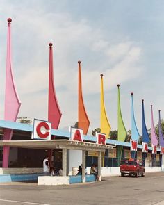 the cars are parked in front of the colorful car dealership with flags on it