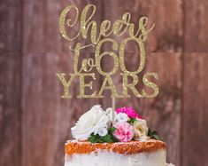 there is a cake that has been decorated with flowers and the words cheers to 100 years on it