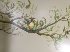 an owl sitting on top of a tree branch with leaves and flowers painted on it