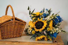 sunflowers and other flowers sit on a table next to a basket