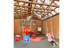 a child swinging on a swing set in a playroom