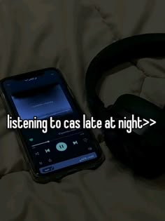 a cell phone with headphones on it sitting next to a pair of headphones