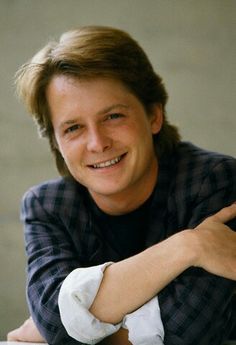 a man sitting at a table with his arms crossed and looking into the camera smiling