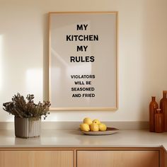 a kitchen with a bowl of lemons on the counter and a poster above it