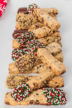 chocolate chip cookies and sprinkles are lined up on a white plate with candy canes