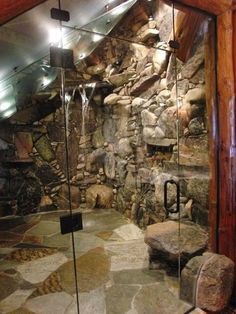 a bathroom with stone walls and flooring next to a large glass door that has a waterfall coming out of it