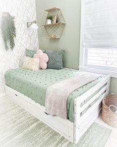 a white bed sitting in a bedroom next to a wall mounted shelf with shelves on it