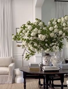 a vase with white flowers on top of a table in front of a couch and coffee table