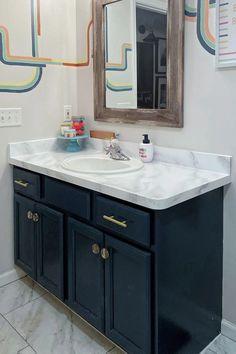 a bathroom with a sink and mirror on the wall above it is decorated in colorful lines