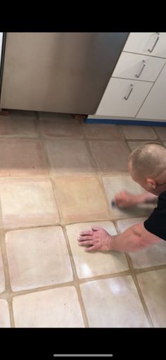 a man is cleaning the floor in his kitchen