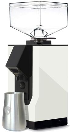 a white and black coffee maker next to a silver cup