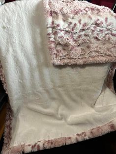 a white and pink blanket sitting on top of a chair