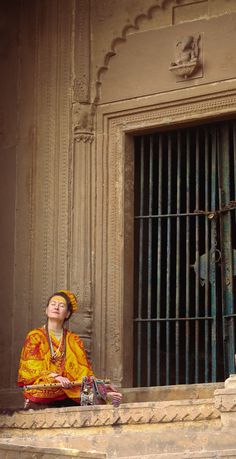 a woman sitting on the ground in front of a jail cell