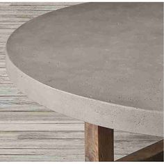 a round concrete table sitting on top of a wooden floor