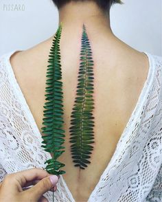 the back of a woman's neck is shown with green leaves on her chest