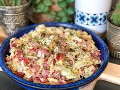 a blue bowl filled with coleslaw on top of a table next to potted plants