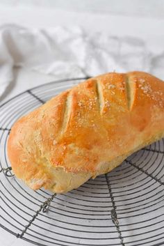 a loaf of bread sitting on top of a wire rack next to a white towel