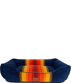 a blue dog bed with an orange and red striped design on the front, sitting against a white background