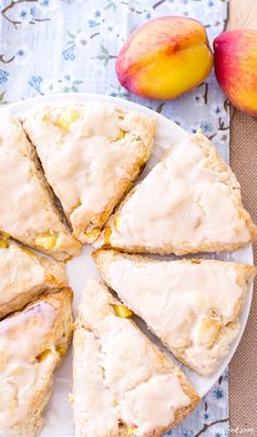 a white plate topped with scones covered in frosting next to two peaches