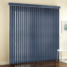 a living room with blue vertical blinds in the window and wood flooring next to it