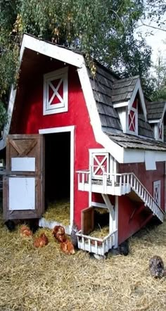 a red and white barn with stairs leading to the door, chicken coop in hay