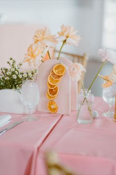 an orange slice cut in half sitting on top of a table next to vases filled with flowers