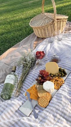 a picnic with cheese, crackers and wine on the blanket in front of it