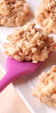 some oatmeal cookies on a white plate with a pink spoon in the foreground