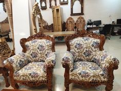 two wooden chairs sitting next to each other in a room with mirrors on the wall