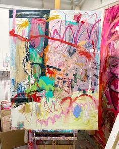 an artist's easel is covered in colorful paint and brush strokes on canvases