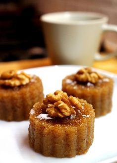 three small desserts on a white plate next to a cup