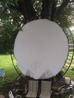 a large white object sitting on top of a lush green field next to a tree