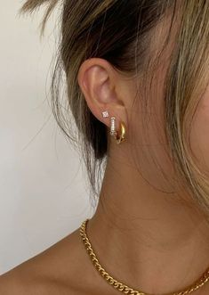 a woman wearing a gold chain necklace and matching earring with a pair of earrings