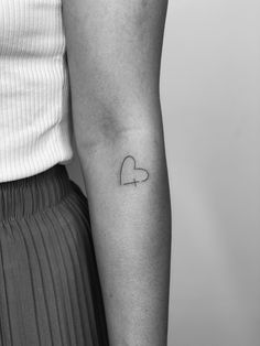 a woman with a small heart tattoo on her arm