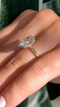 a woman's hand holding an engagement ring with a large diamond on the side