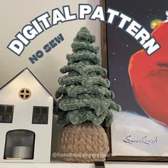 a knitted christmas tree next to a small house with a digital pattern on it