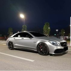 a silver car is parked on the side of the road at night with street lights in the background