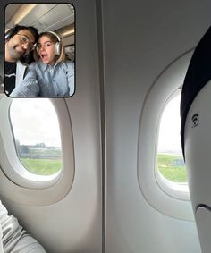 a man and woman sitting on an airplane looking out the window with their headsets up