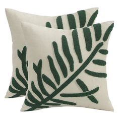 two pillows with green leaves on them, one in white and the other in dark green