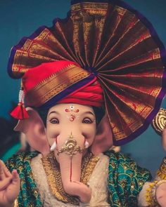 an elephant with a red turban on it's head and two hands in front of its face