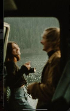 two people are sitting in the back of a car looking at each other and smiling