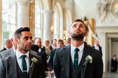 two men in suits are standing next to each other at a wedding ceremony, looking up into the sky