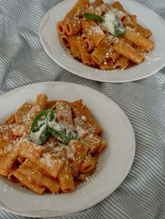 two white plates filled with pasta and sauce